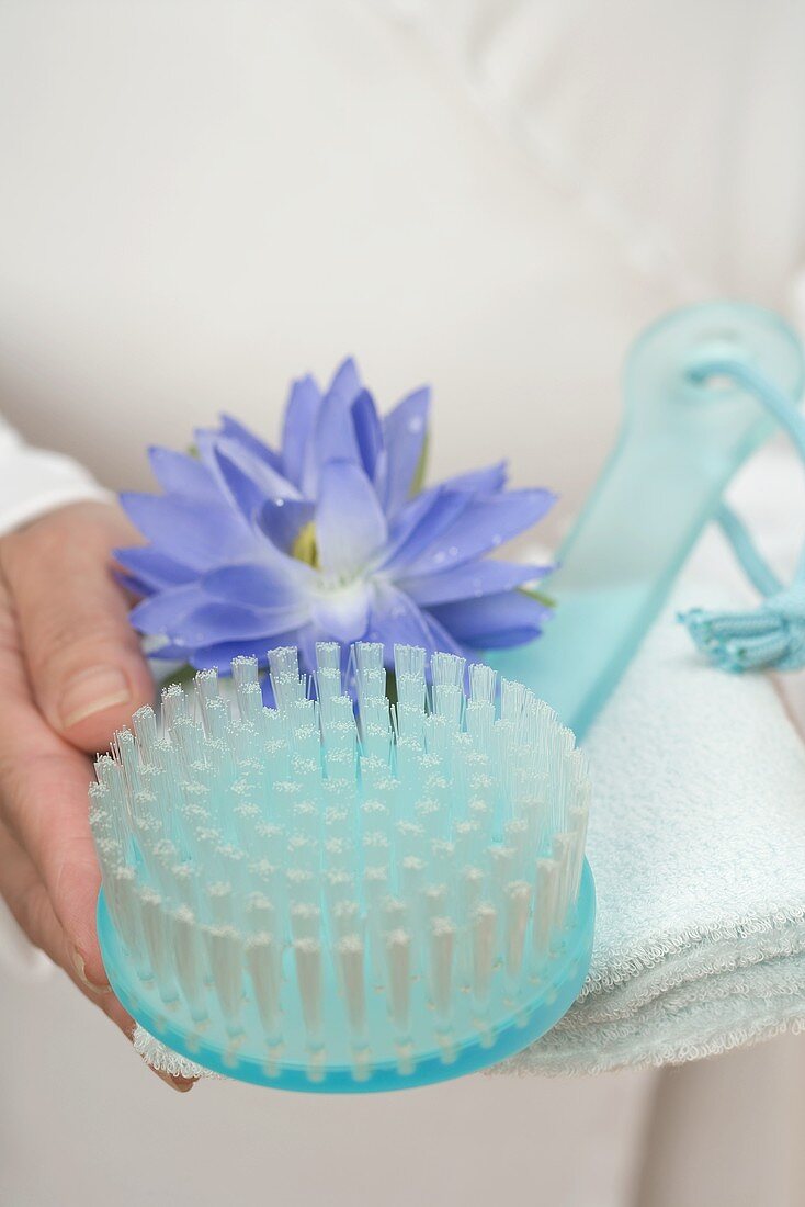 Hands holding brush, water lily and towel