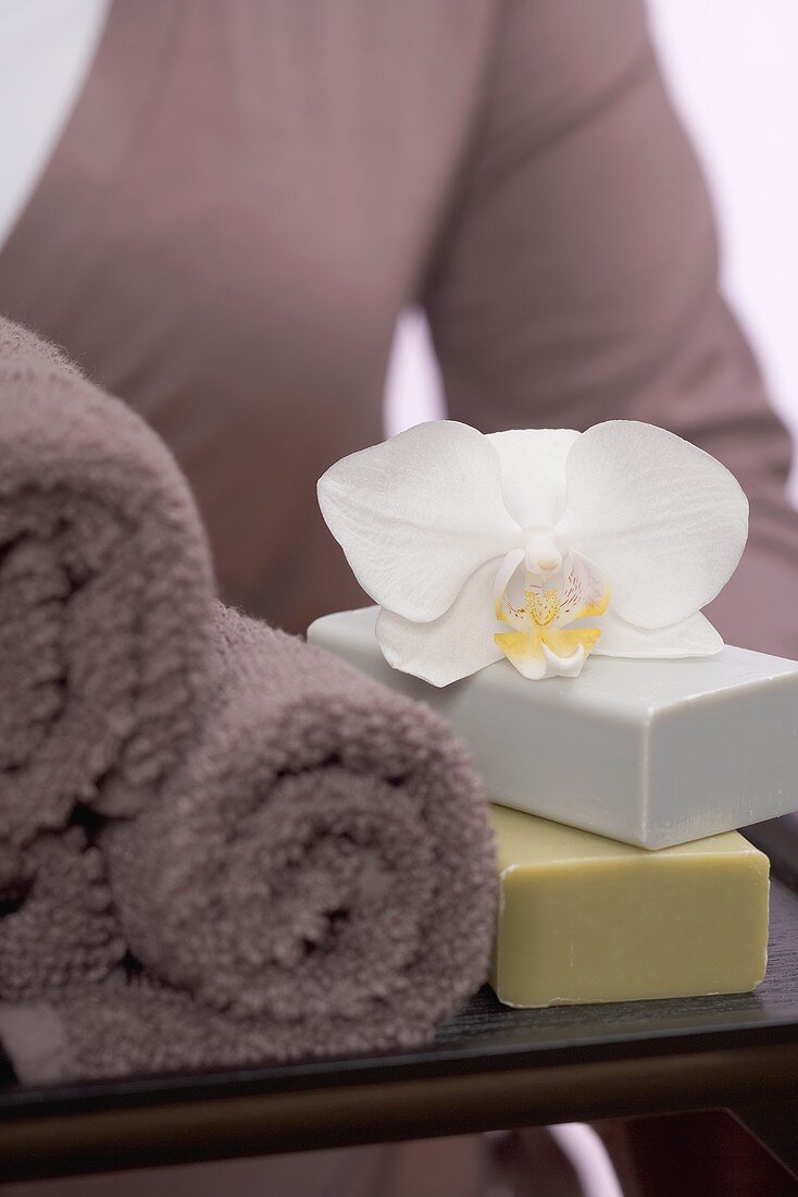 Woman holding towels, soaps and orchid on tray