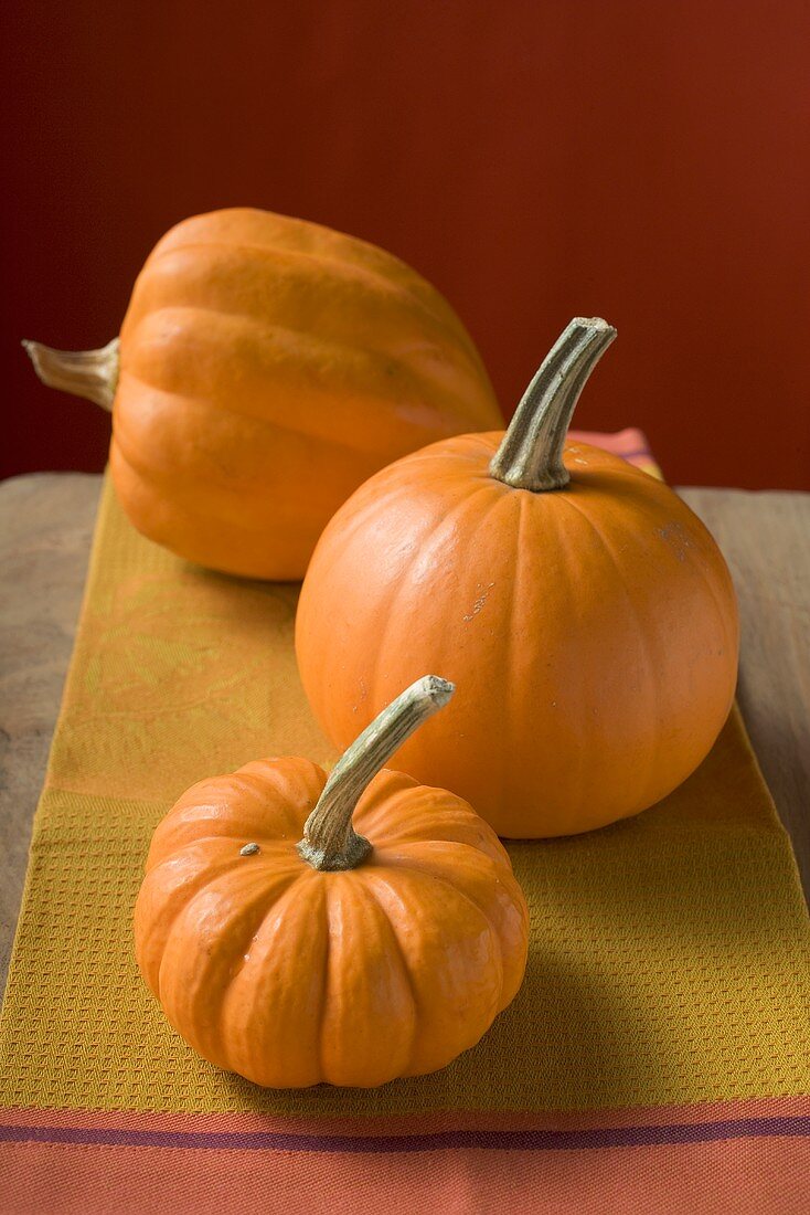 Three orange pumpkins on cloth