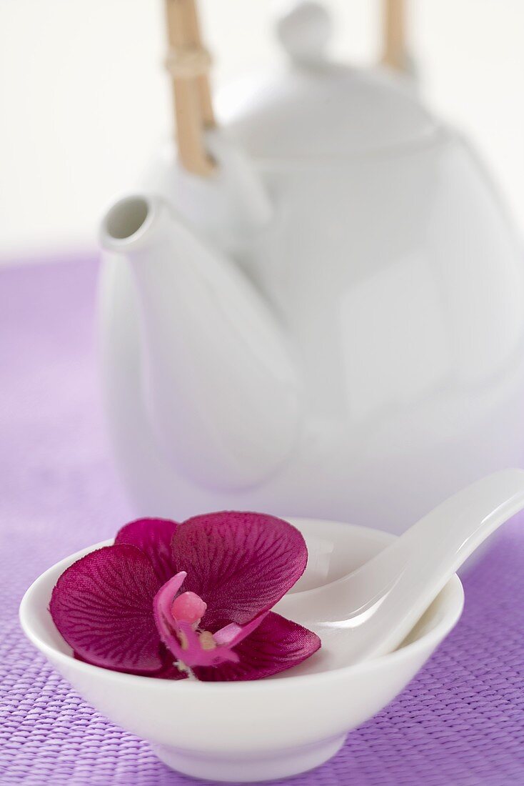 Teekanne und Schale mit Löffel und Orchidee