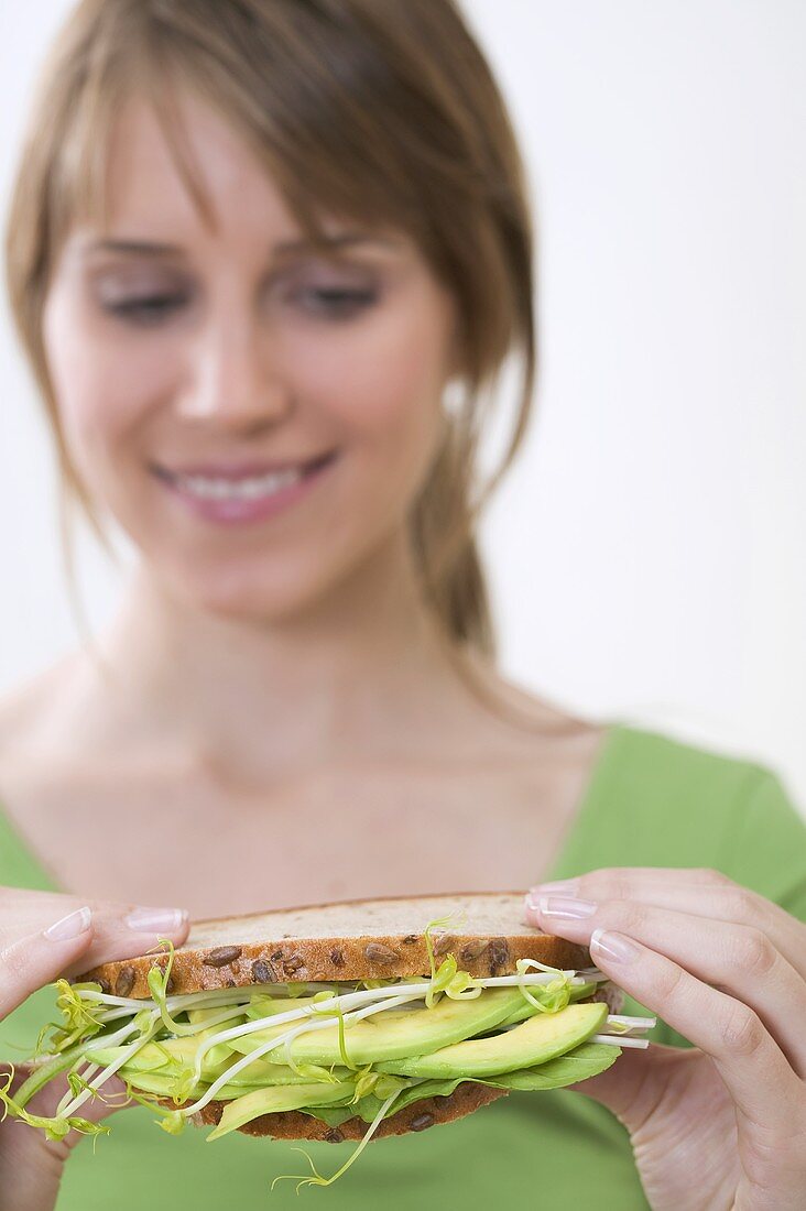 Woman holding healthy avocado and sprout sandwich