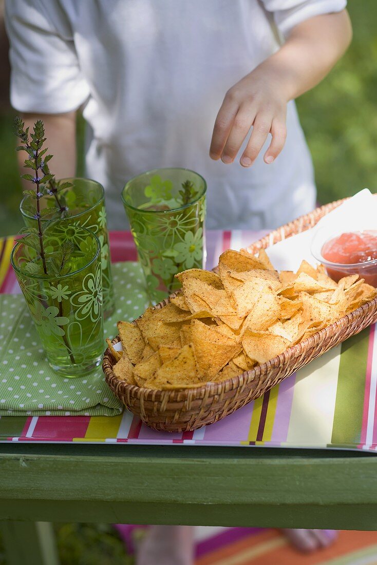 Tortilla chips, salsa and drinks, child in background