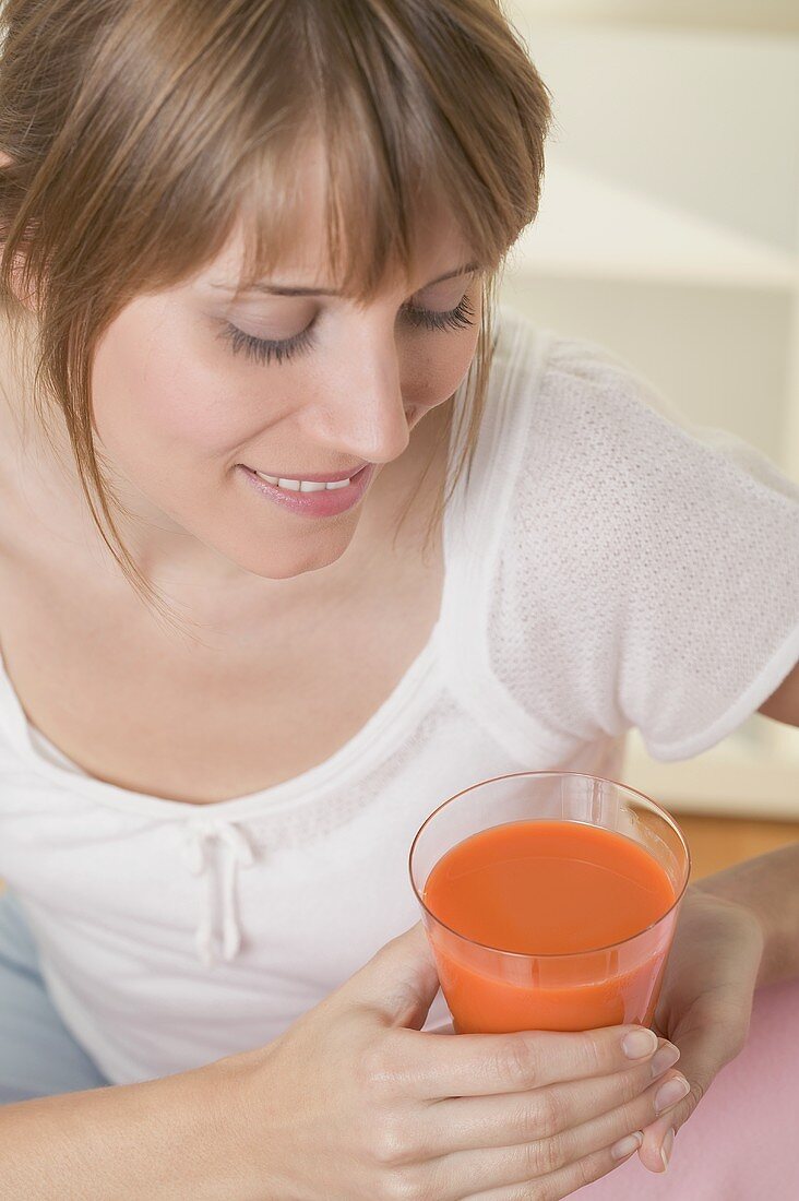 Woman holding glass of carrot juice