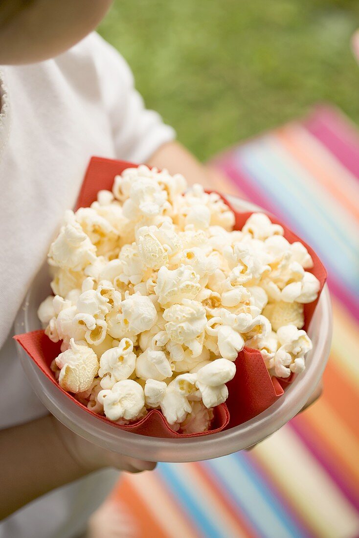 Child holding bowl of popcorn