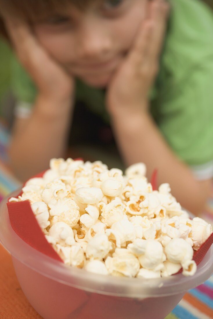 Popcorn in Plastikschale, Kind im Hintergrund