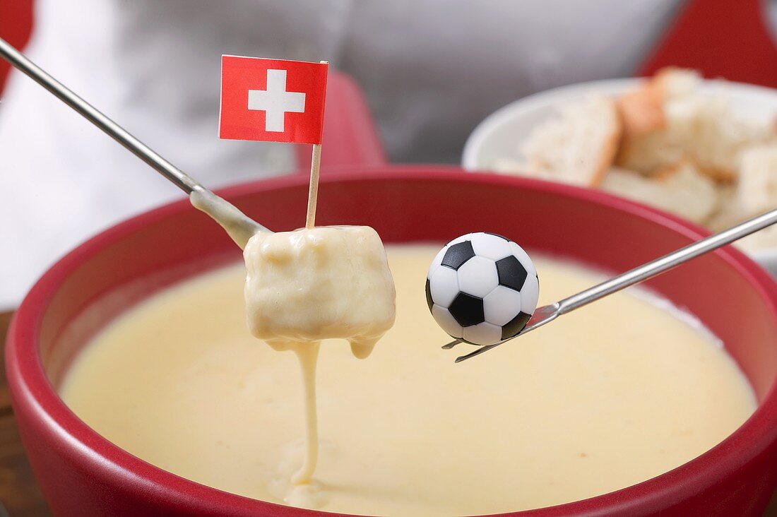 Woman eating cheese fondue, toy football on fondue fork