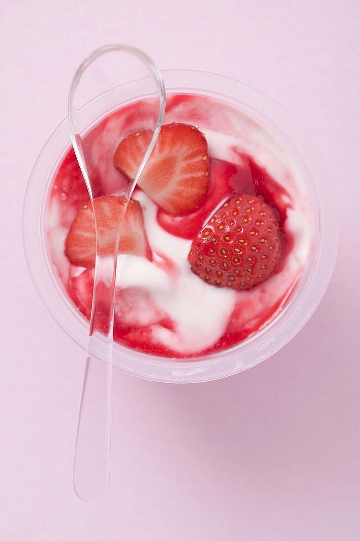 Erdbeerjoghurt im Plastikbecher mit Löffel (Draufsicht)