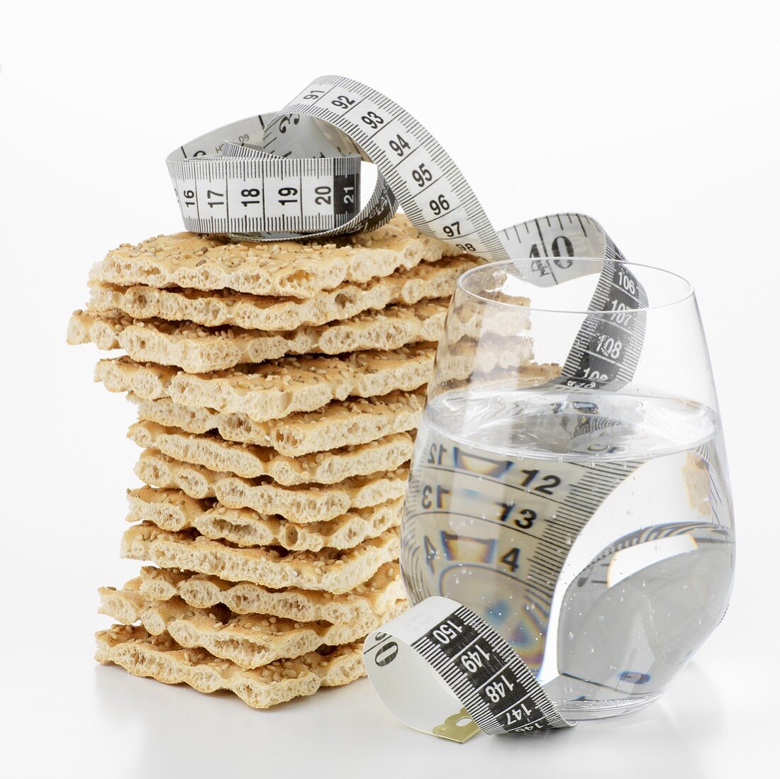 Crispbread, in a pile, & glass of water with tape measure