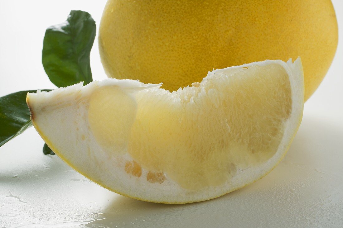 Wedge of pomelo, whole pomelo and leaves