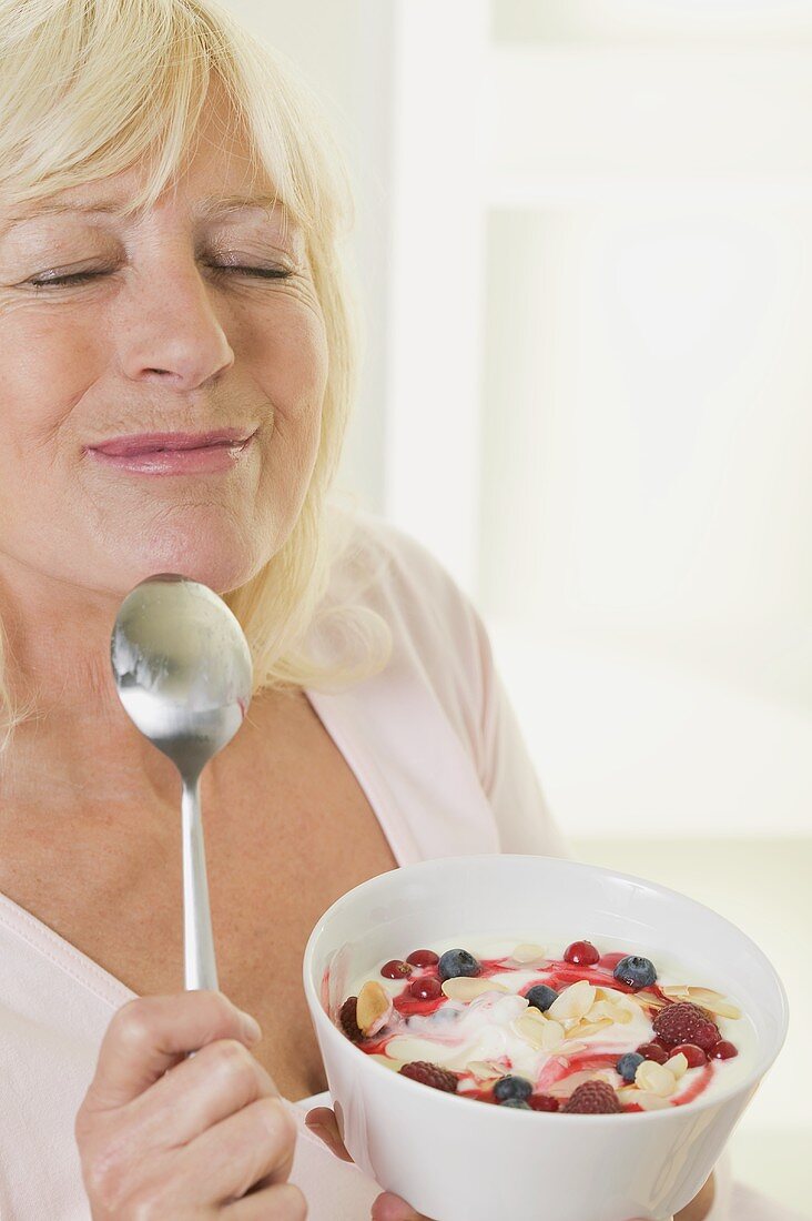 Frau geniesst Joghurt mit Beeren und Mandelblättchen