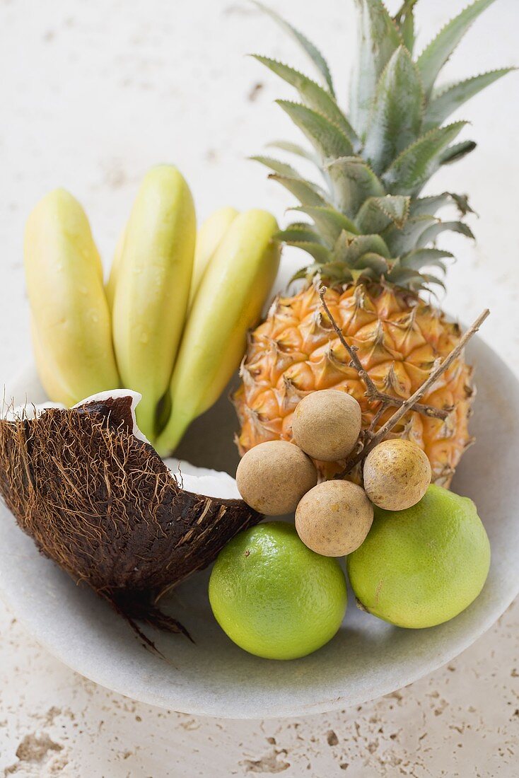 Obstschale mit exotischen Früchten, Limetten und Kokosnuss