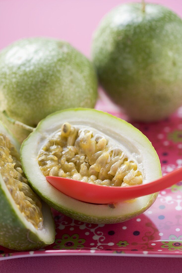 Green passion fruits, one halved, with spoon