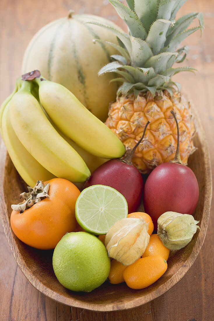 Exotische Früchte und Zitrusfrüchte in Holzschale