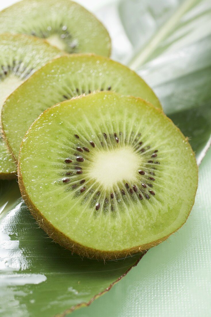 Several slices of kiwi fruit on leaf
