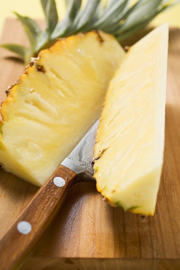 Wedges of pineapple on chopping board with knife