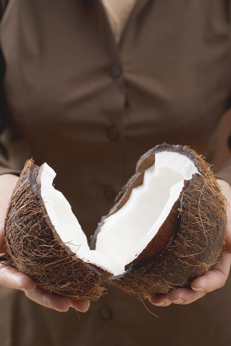 Woman holding halved coconut