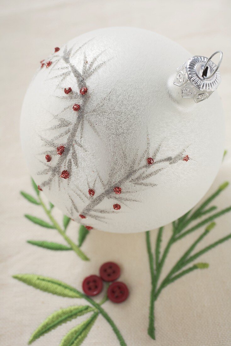 White Christmas tree bauble on embroidered linen cloth