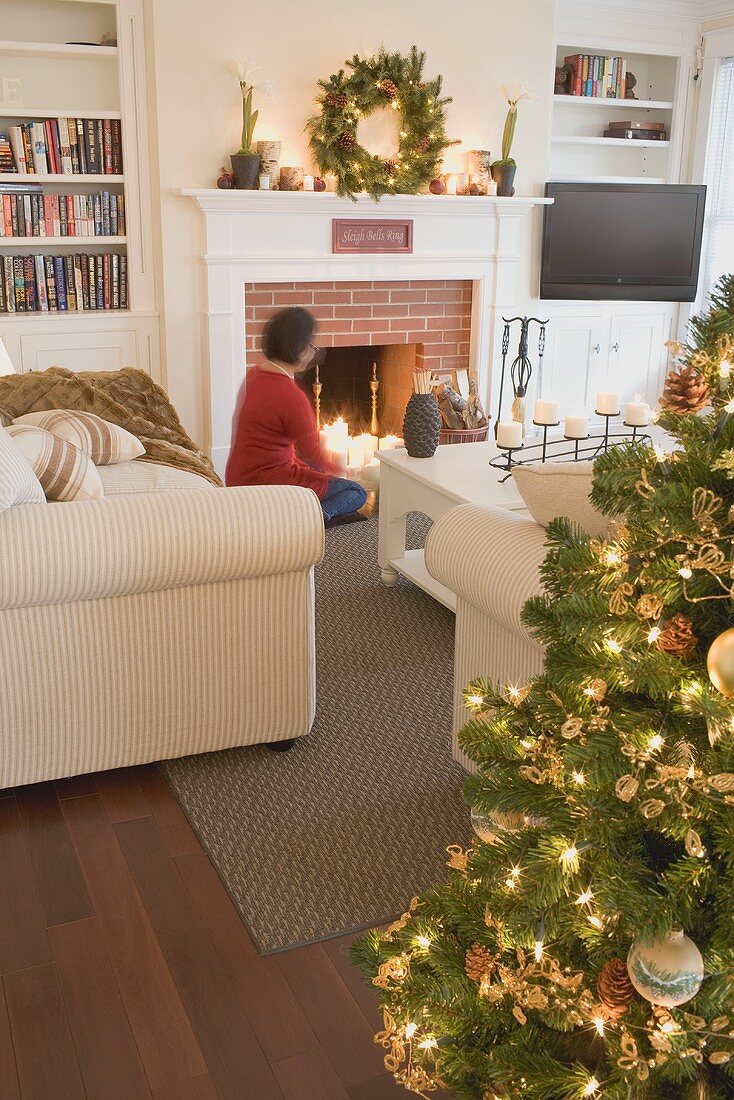Woman by fireplace in living room decorated for Christmas