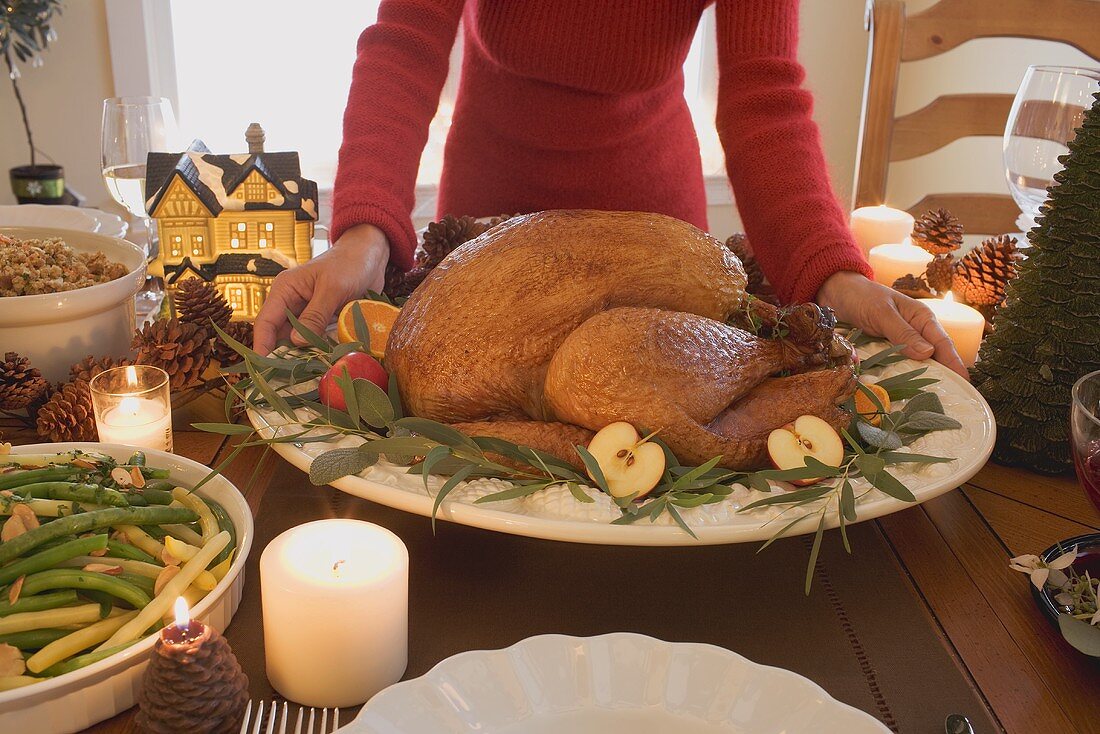 Frau stellt gebratenen Turkey auf Weihnachtstisch (USA)
