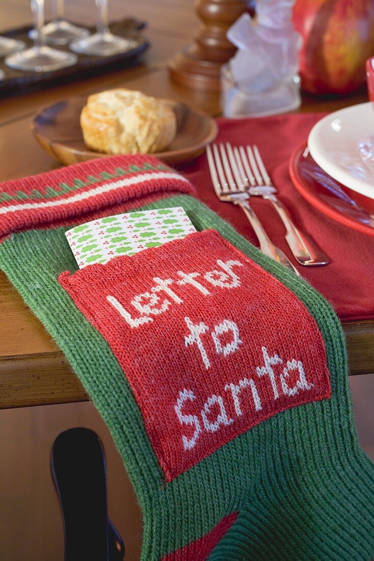 Stiefel mit Brief an Santa Claus neben weihnachtlichem Gedeck