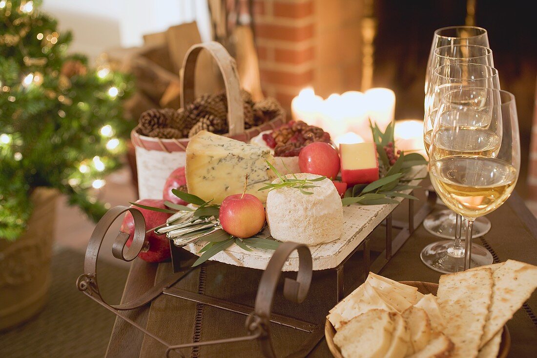 Käseplatte, Cracker und Weißwein vor Kamin (weihnachtlich)