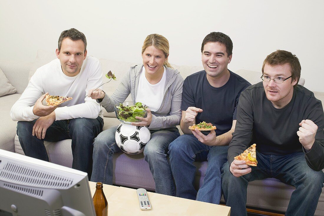 Friends in front of TV with pizza, salad and football