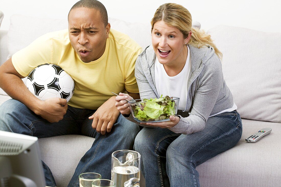 Couple in front of TV with football and salad