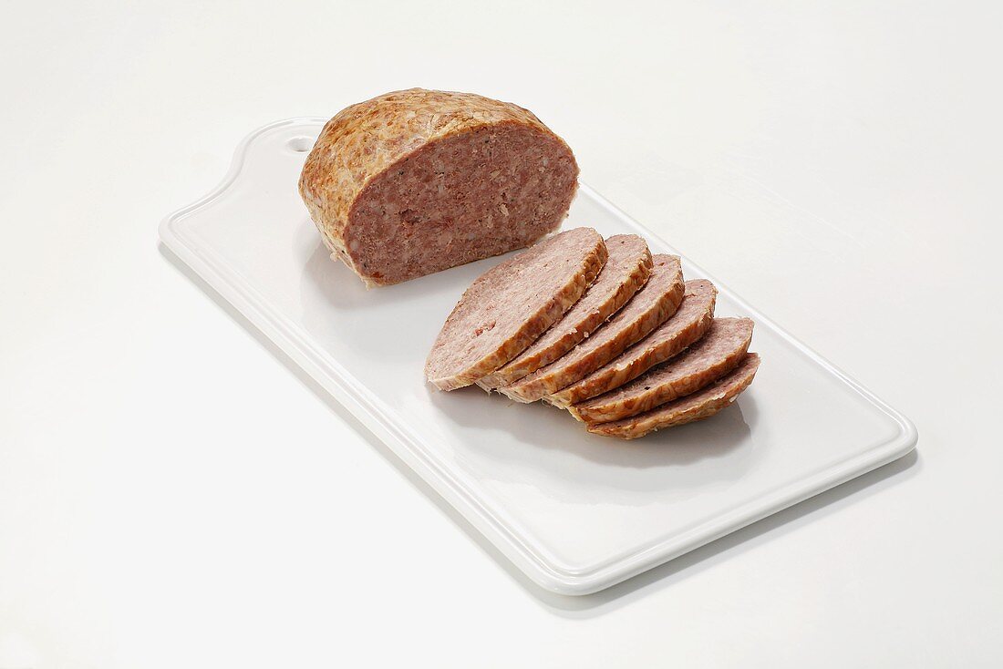 Coarse Leberkäse (type of meatloaf), partly sliced, on chopping board