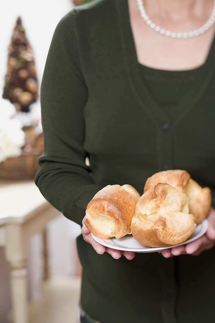 Woman holding plate of popovers (Christmas)