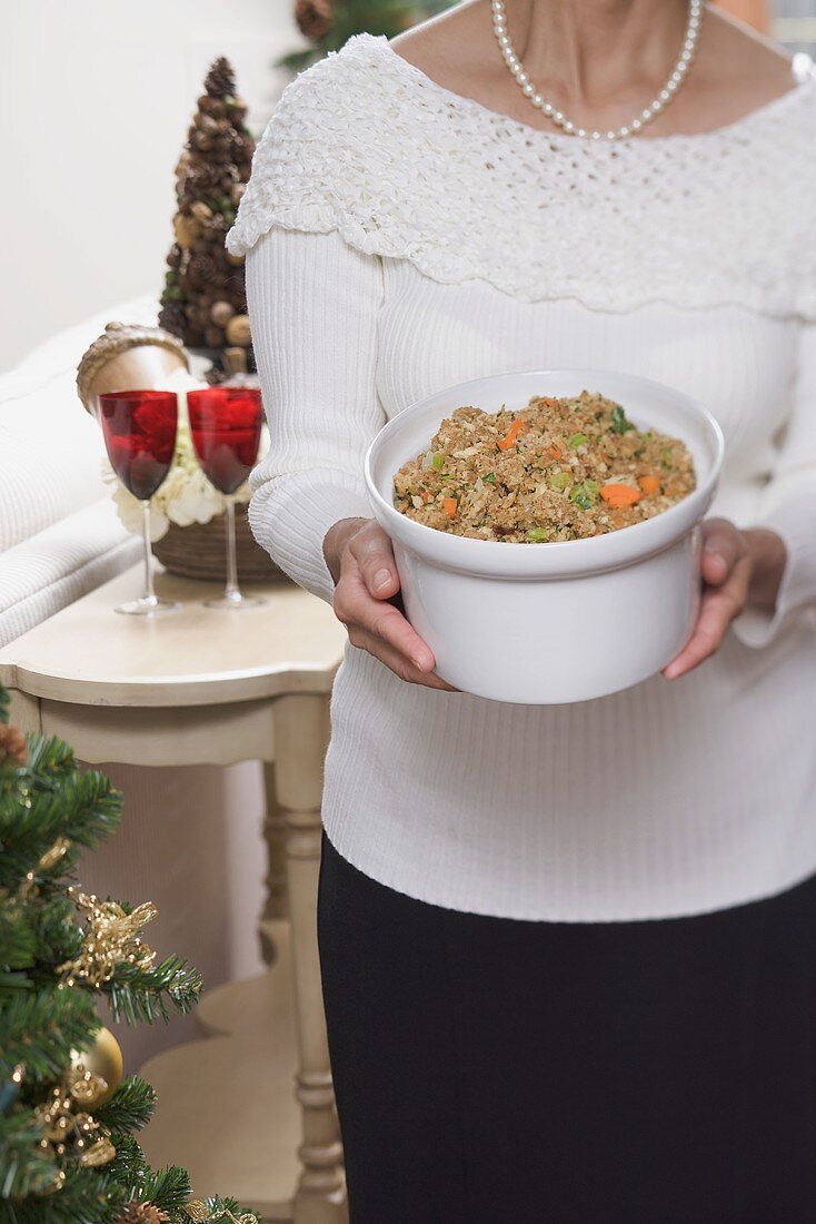 Woman holding large dish of bread stuffing (Christmas)