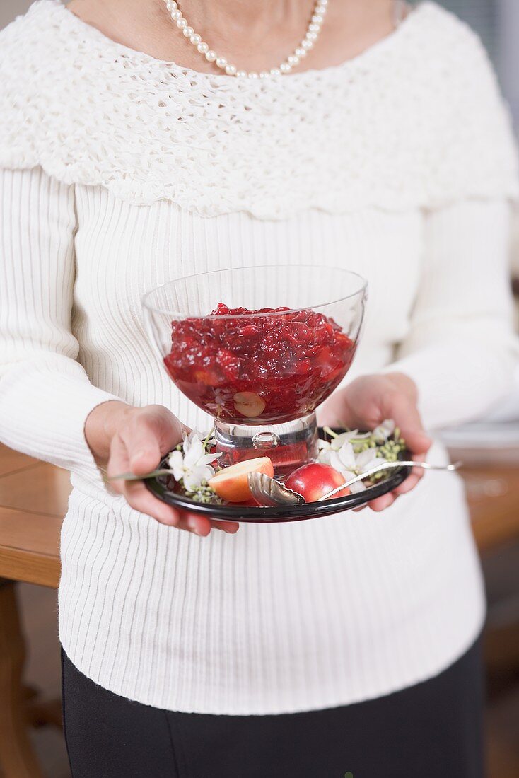 Frau hält Cranberrysauce in Glasschale (weihnachtlich)