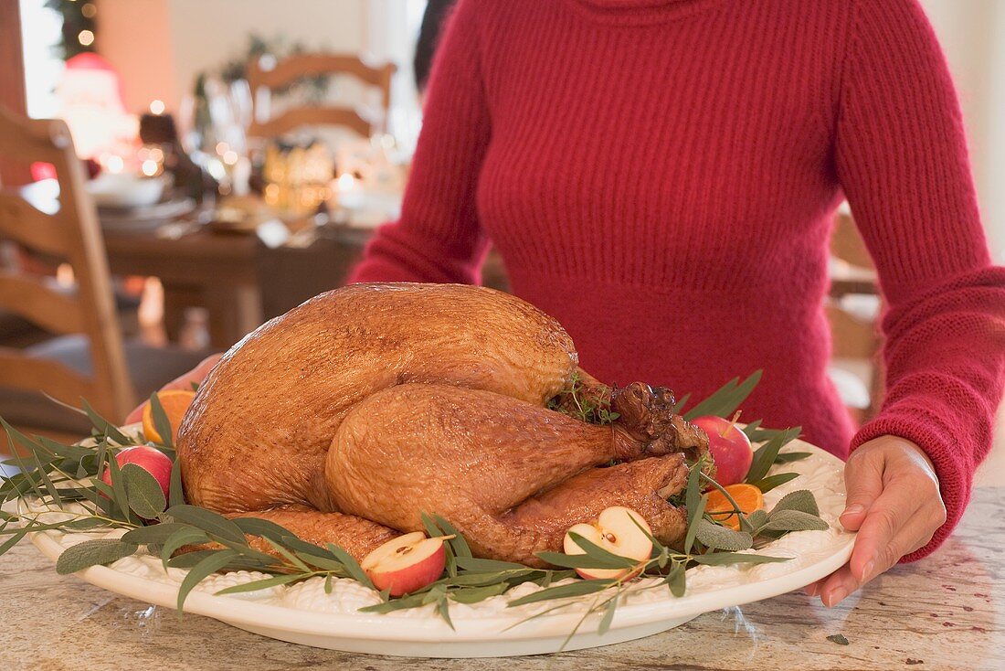 Woman holding roast turkey on platter