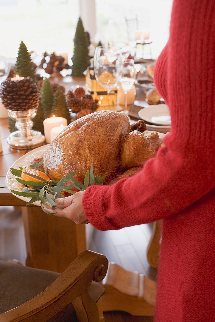 Frau serviert gebratenen Truthahn zu Weihnachten