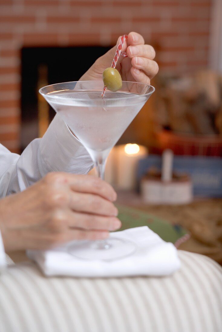Hands holding glass of Martini with olive