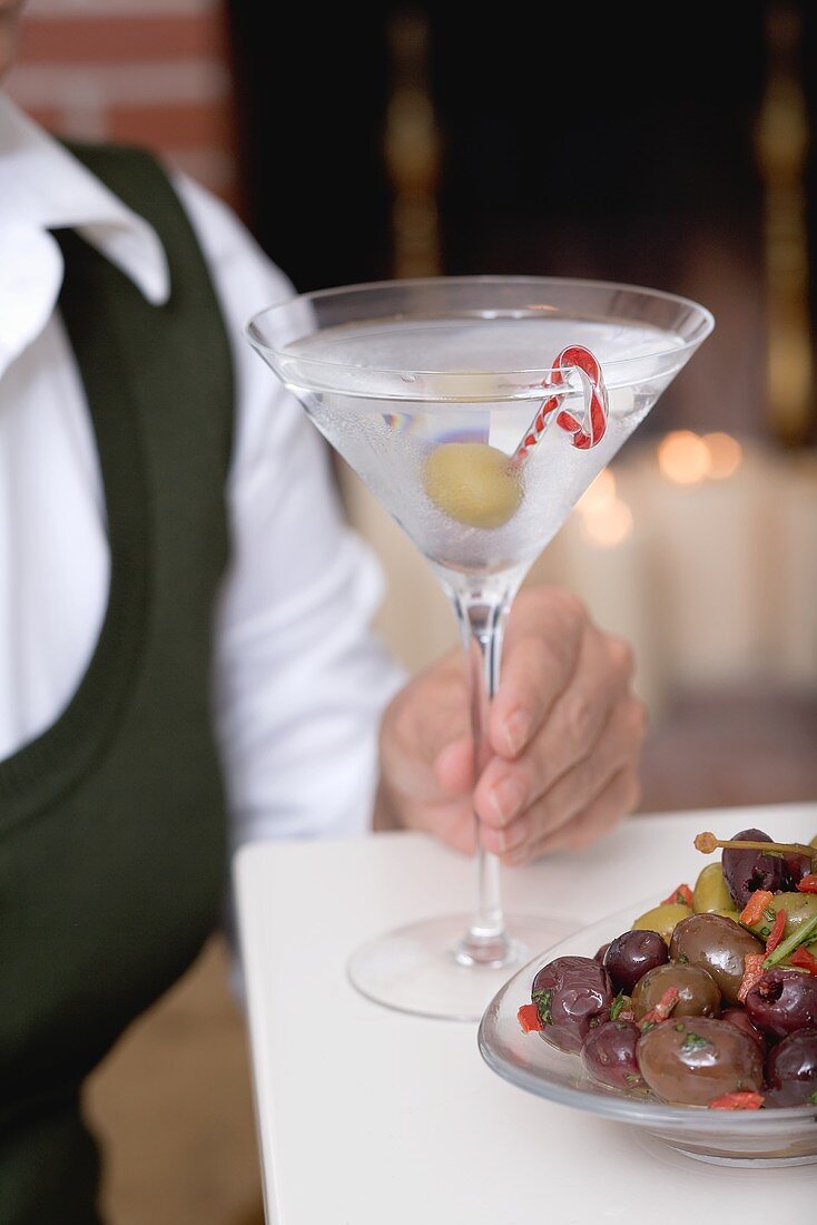 Frau hält Glas Martini mit Olive