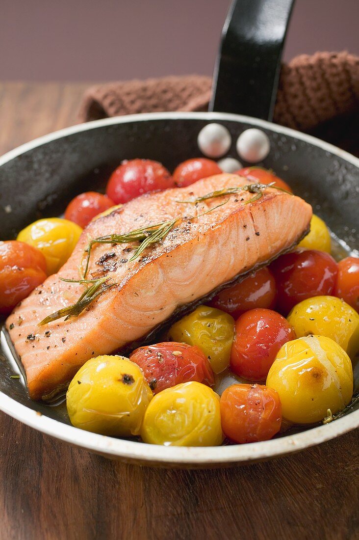 Fried salmon and cherry tomatoes in frying pan