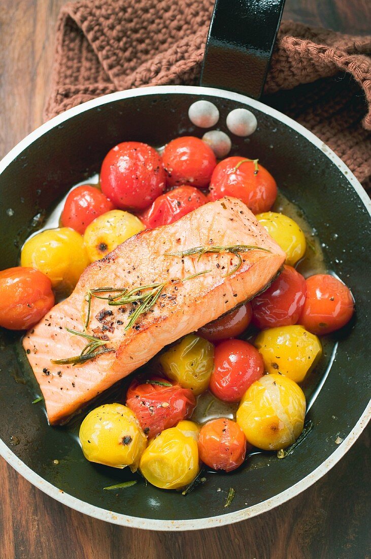 Fried salmon fillet and cherry tomatoes in frying pan