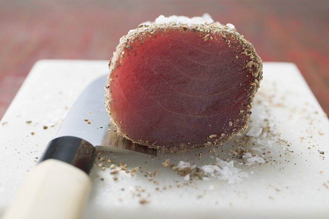 Raw tuna fillet with salt and pepper on knife