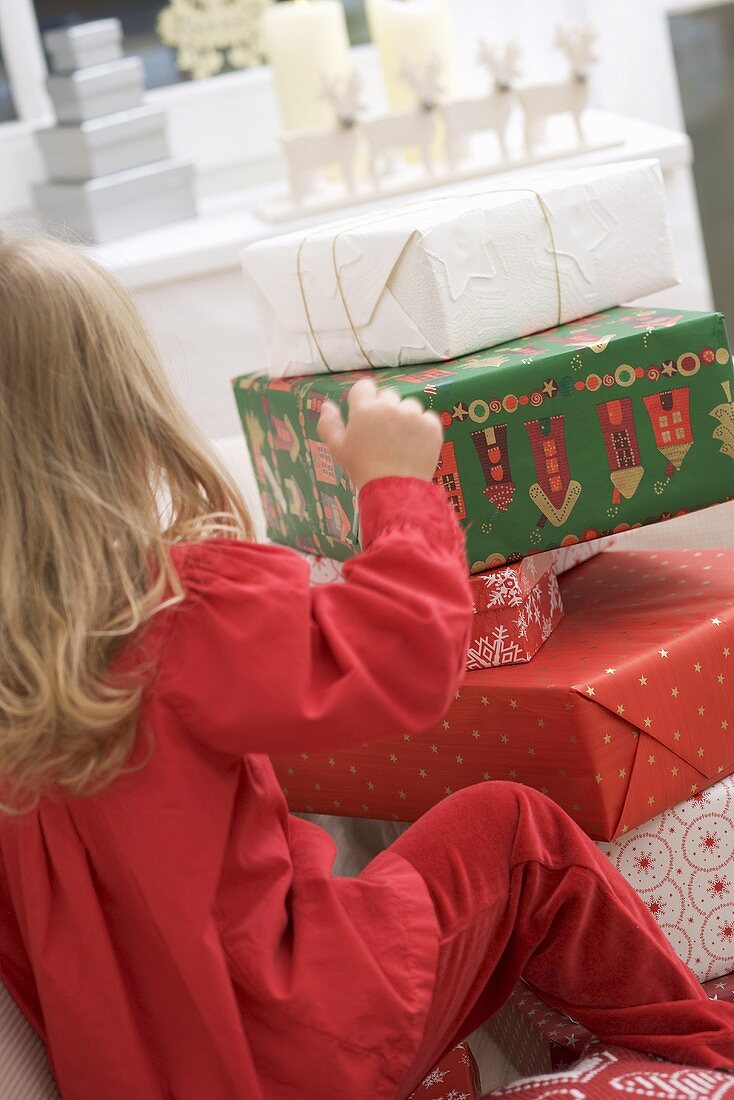 Kleines Mädchen vor gestapelten Weihnachtspaketen