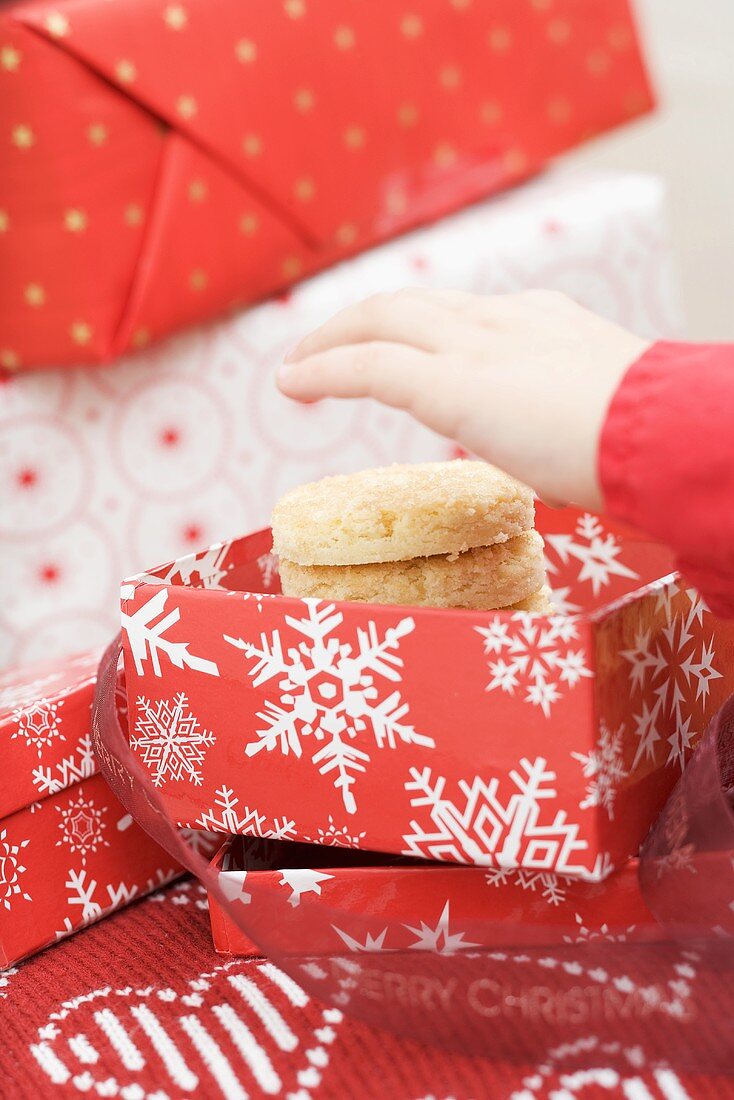 Child's hand reaching for Christmas biscuits in box