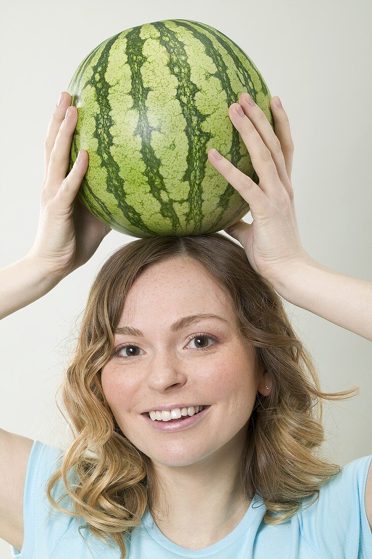 Frau balanciert Wassermelone auf dem Kopf