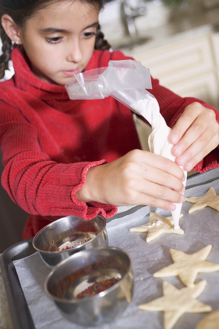 Mädchen verziert Plätzchen mit Spritztülle