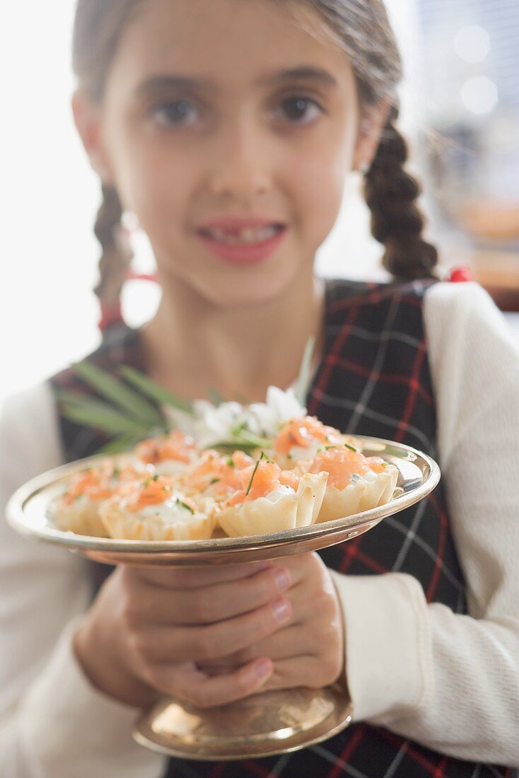 Mädchen hält Silberschale mit Lachspastetchen