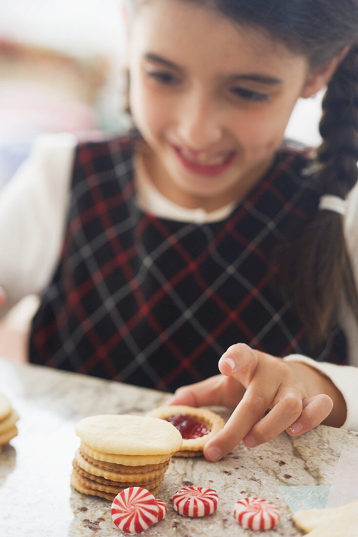 Mädchen nimmt Marmeladenplätzchen vom Tisch