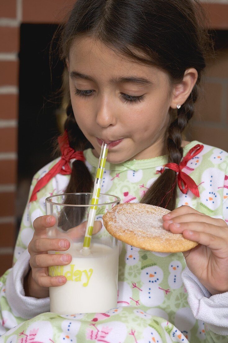 Girl drinking milk and holding biscuit