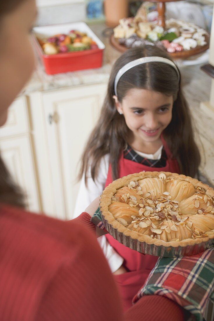 Young woman holding apple tart, girl in background