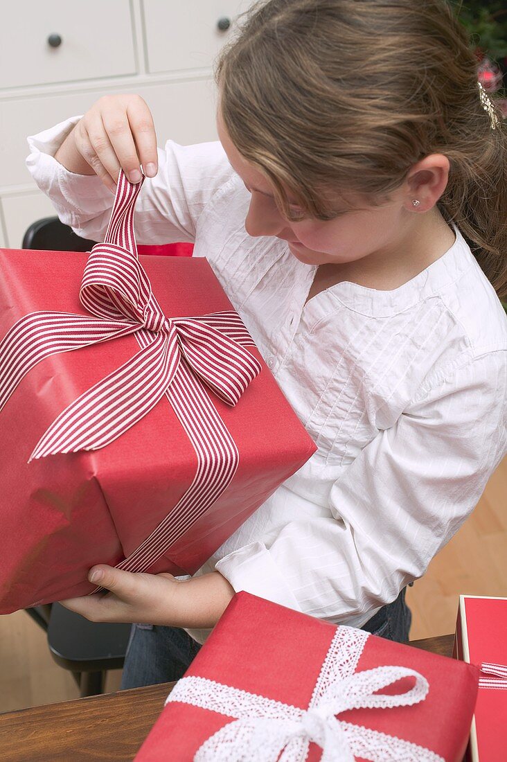Mädchen öffnet Schachtel mit Weihnachtsgeschenk