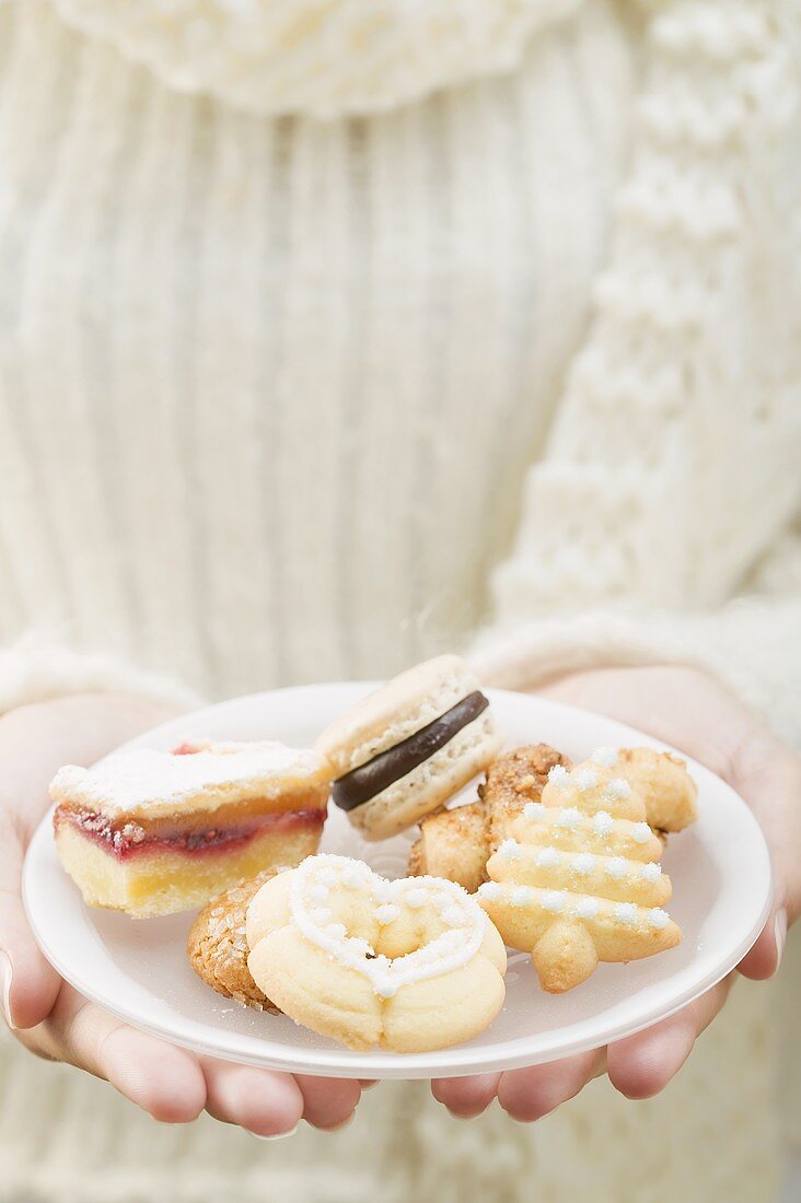 Woman holding assorted Christmas biscuits on plate