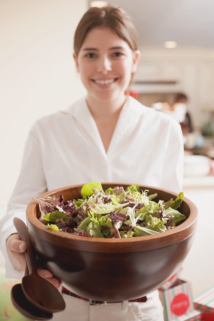 Young woman holding large bowl of salad