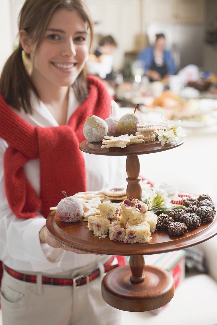 Junge Frau hält Etagere mit Weihnachtsgebäck